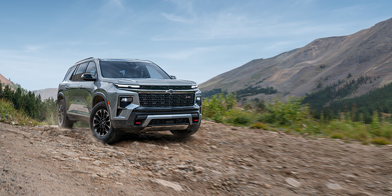 Silver Chevrolet Traverse driving on a rocky mountain trail.